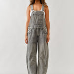 Person wearing gray denim overalls on a white background