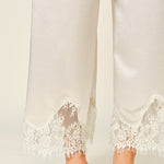 Close-up of champagne satin pants with delicate lace trim hem detail