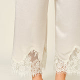 Close-up of champagne satin pants with delicate lace trim hem detail