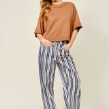 Woman wearing a brown top and striped pants on a plain background