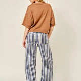 Woman wearing a brown sweater and striped pants on a beige background