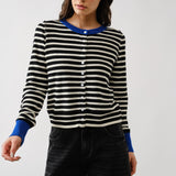 Woman wearing a black and white striped sweater with blue cuffs and collar against a white background