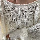 Close-up of a person wearing an off-shoulder knit sweater.