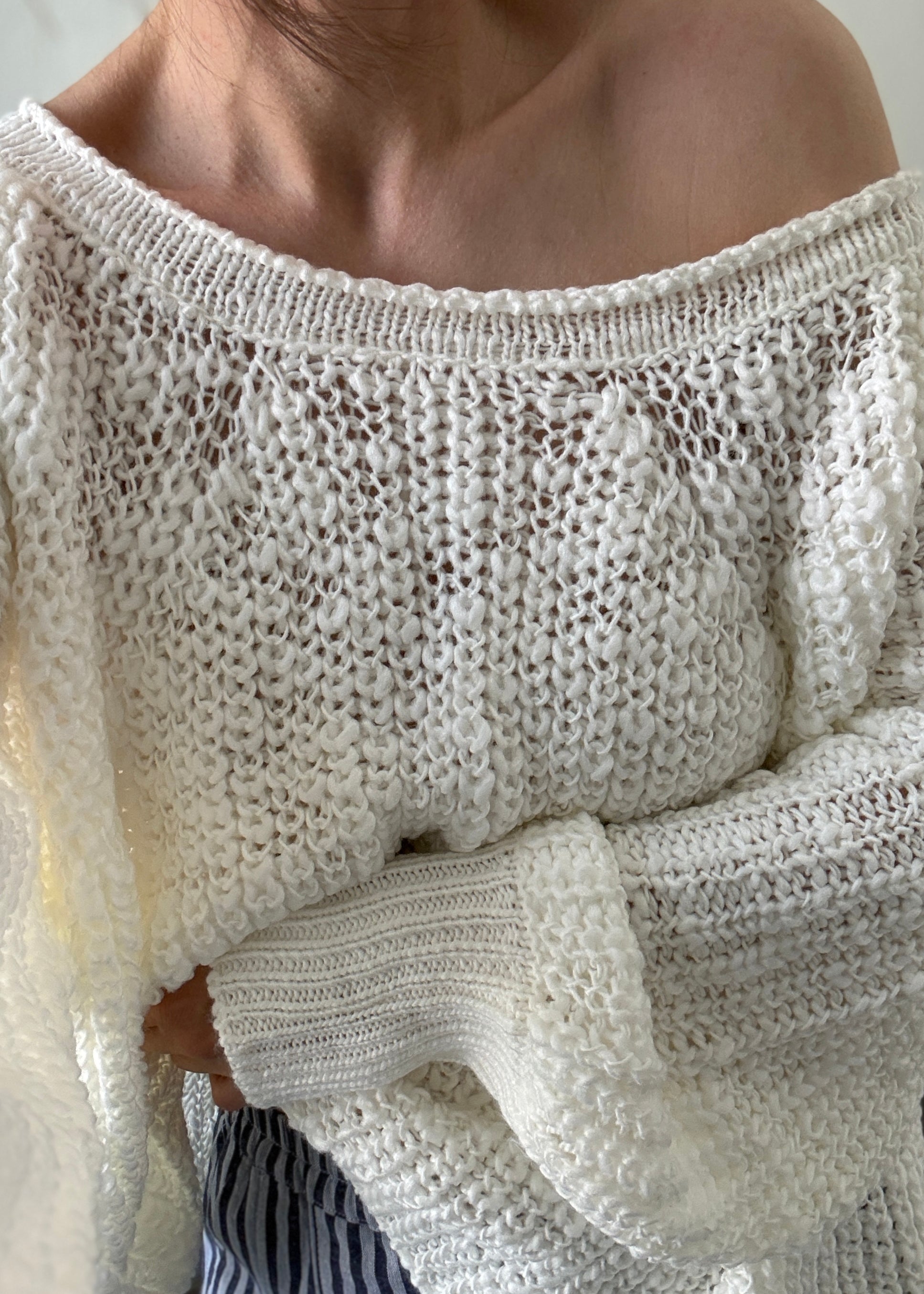 Close-up of a person wearing an off-shoulder knit sweater.