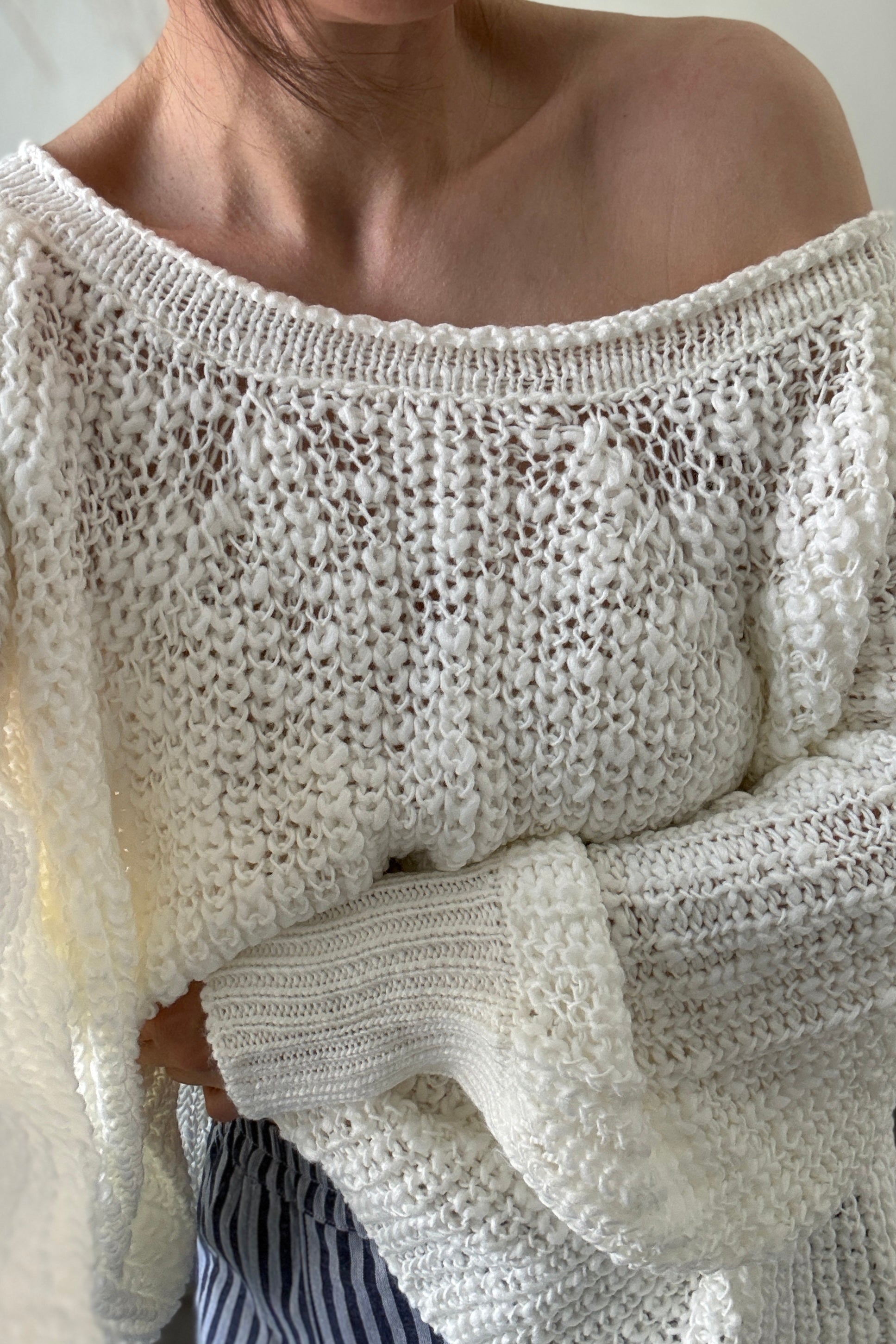 Close-up of a person wearing an off-shoulder knit sweater.
