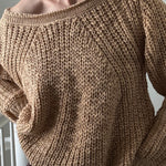 Person wearing a brown knitted sweater with a blurred background
