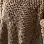 Close-up of a brown knitted sweater with a textured pattern.