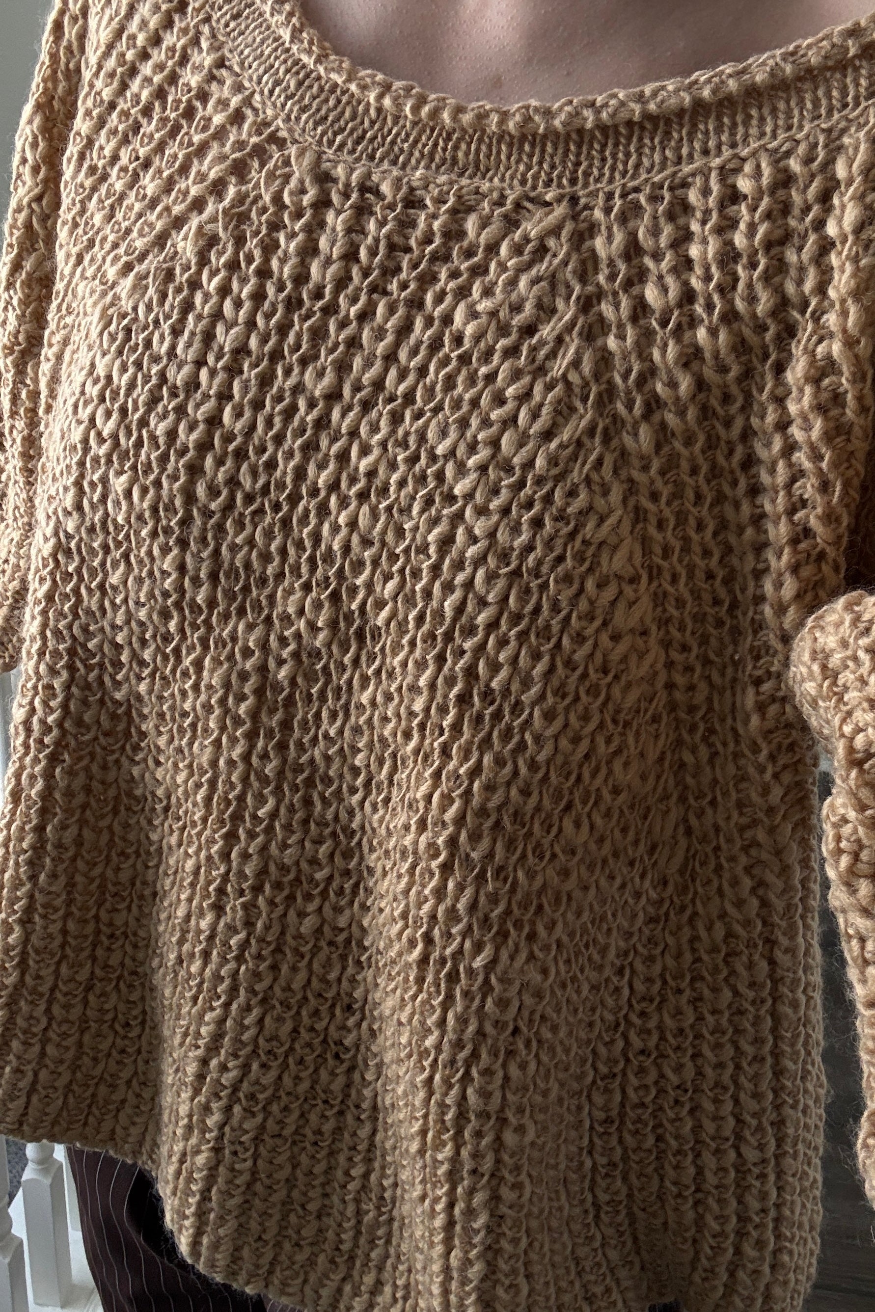 Close-up of a brown knitted sweater with a textured pattern.