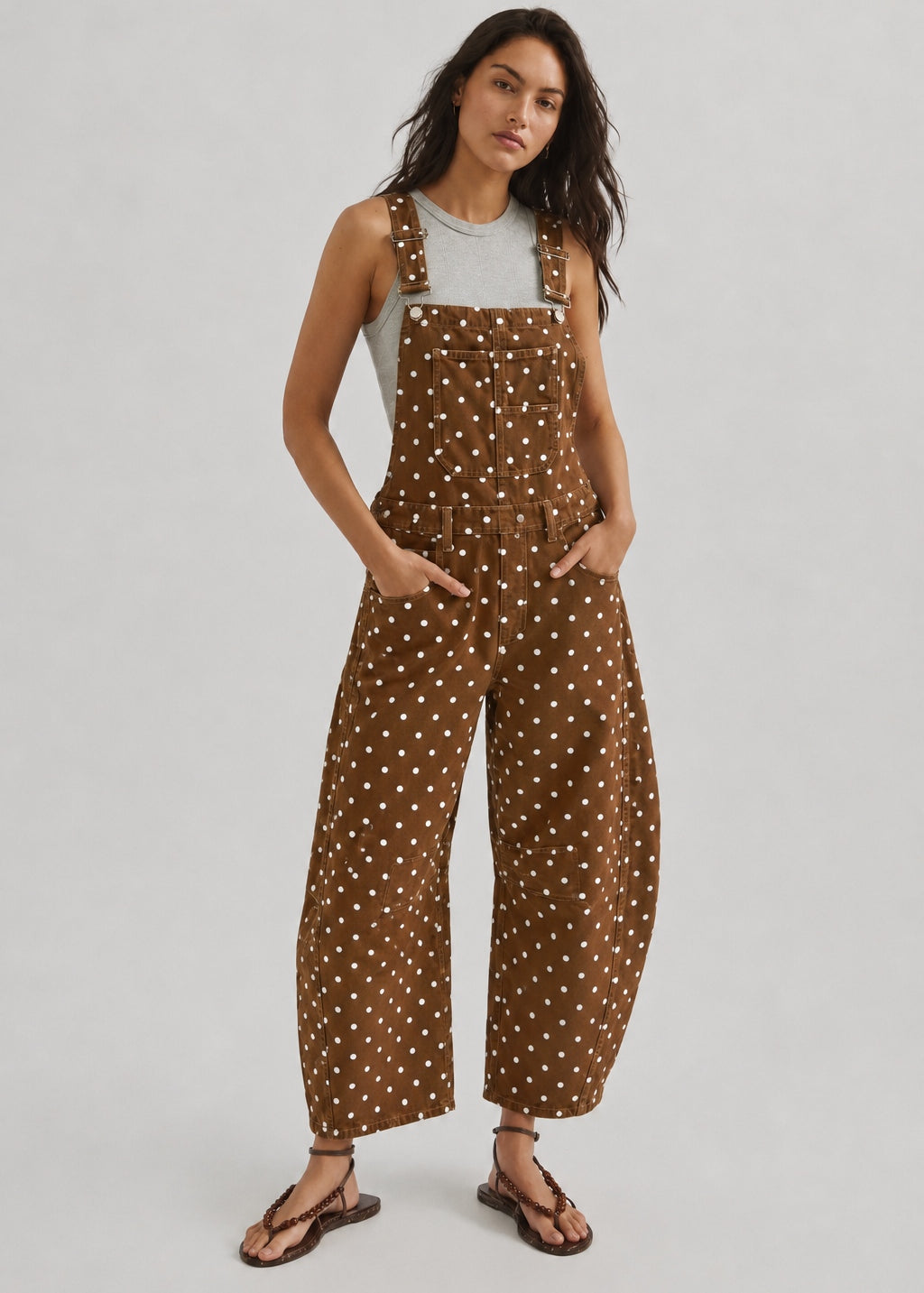 Full-length studio view of Aaron & Amber brown polka dot denim overalls with curved barrel legs