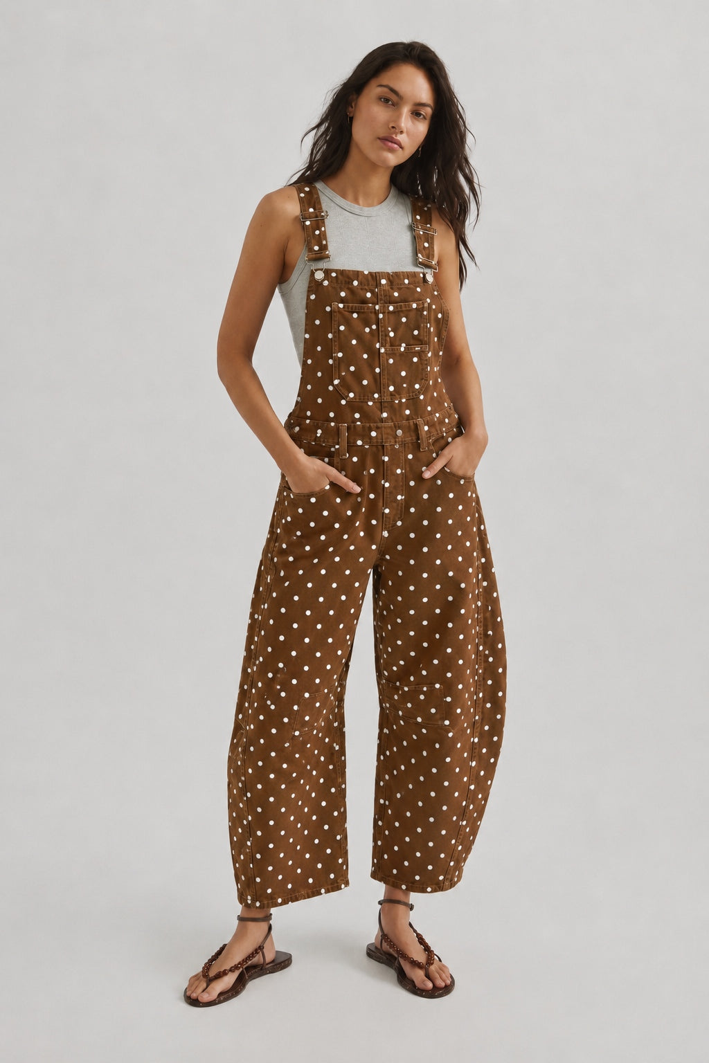 Full-length studio view of Aaron & Amber brown polka dot denim overalls with curved barrel legs