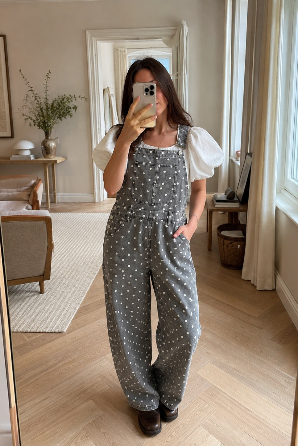 Woman wearing Aaron & Amber black polka dot barrel-leg denim overalls in a casual mirror selfie