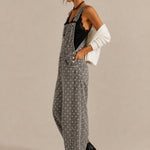 Side view of Aaron & Amber black polka dot denim overalls with curved barrel legs