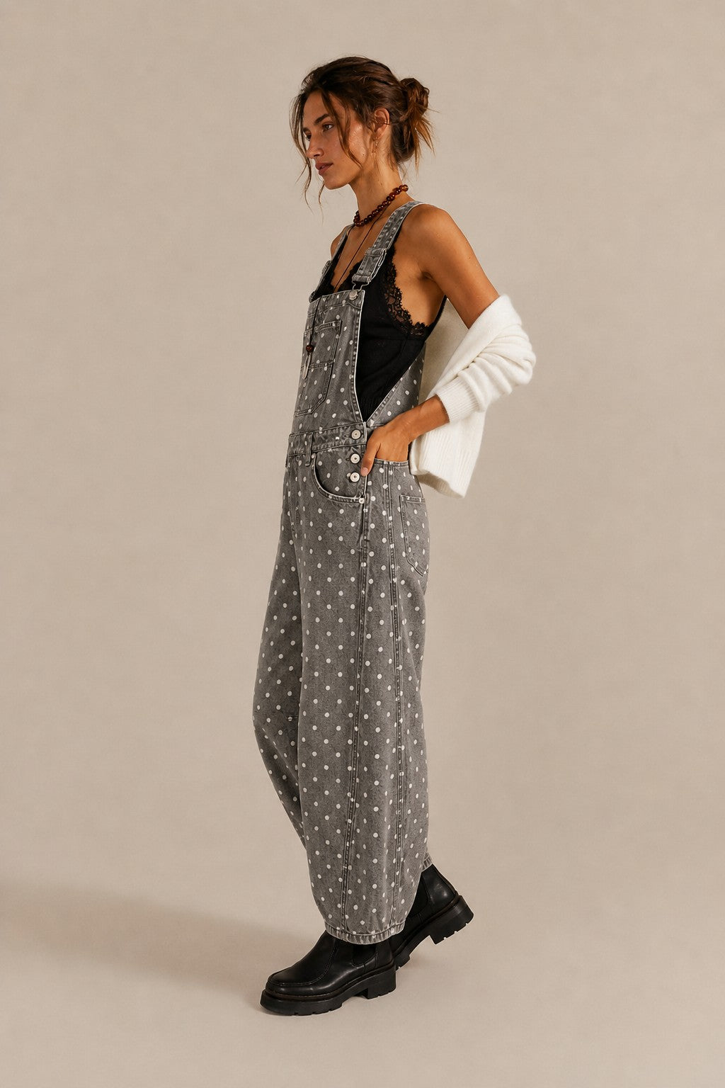 Side view of Aaron & Amber black polka dot denim overalls with curved barrel legs
