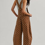 Back view of woman wearing Aaron & Amber brown polka dot barrel-leg denim overalls