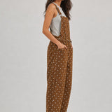 Side view of woman wearing Aaron & Amber brown polka dot barrel-leg denim overalls