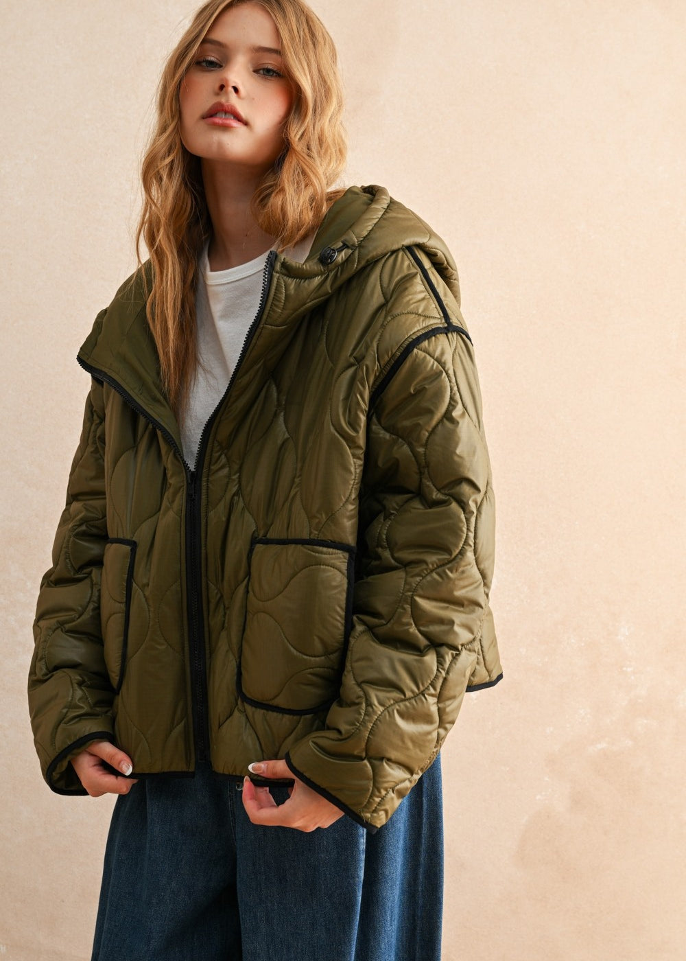 Woman is wearing  the olive hooded quilted puffer jacket styled with jeans for everyday layering