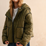 Woman is wearing  the olive hooded quilted puffer jacket styled with jeans for everyday layering