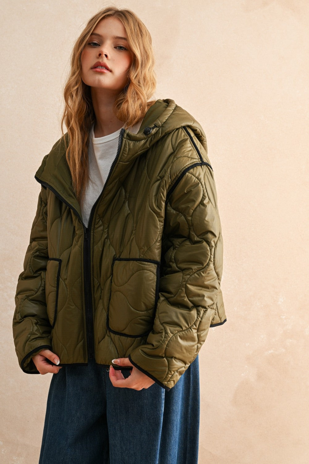 Woman is wearing  the olive hooded quilted puffer jacket styled with jeans for everyday layering