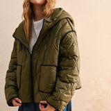 Woman is wearing  the olive hooded quilted puffer jacket styled with jeans for everyday layering