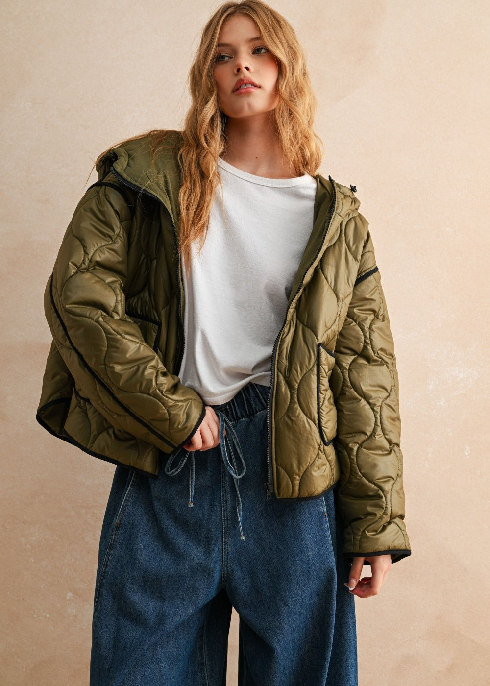 Model is posing wearing the olive Ava hooded quilted puffer jacket with zip closure and pockets
