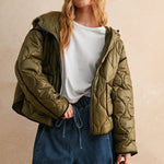 Model is posing wearing the olive Ava hooded quilted puffer jacket with zip closure and pockets