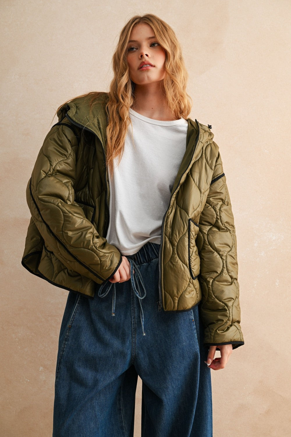 Model is posing wearing the olive Ava hooded quilted puffer jacket with zip closure and pockets
