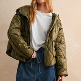 Model is posing wearing the olive Ava hooded quilted puffer jacket with zip closure and pockets