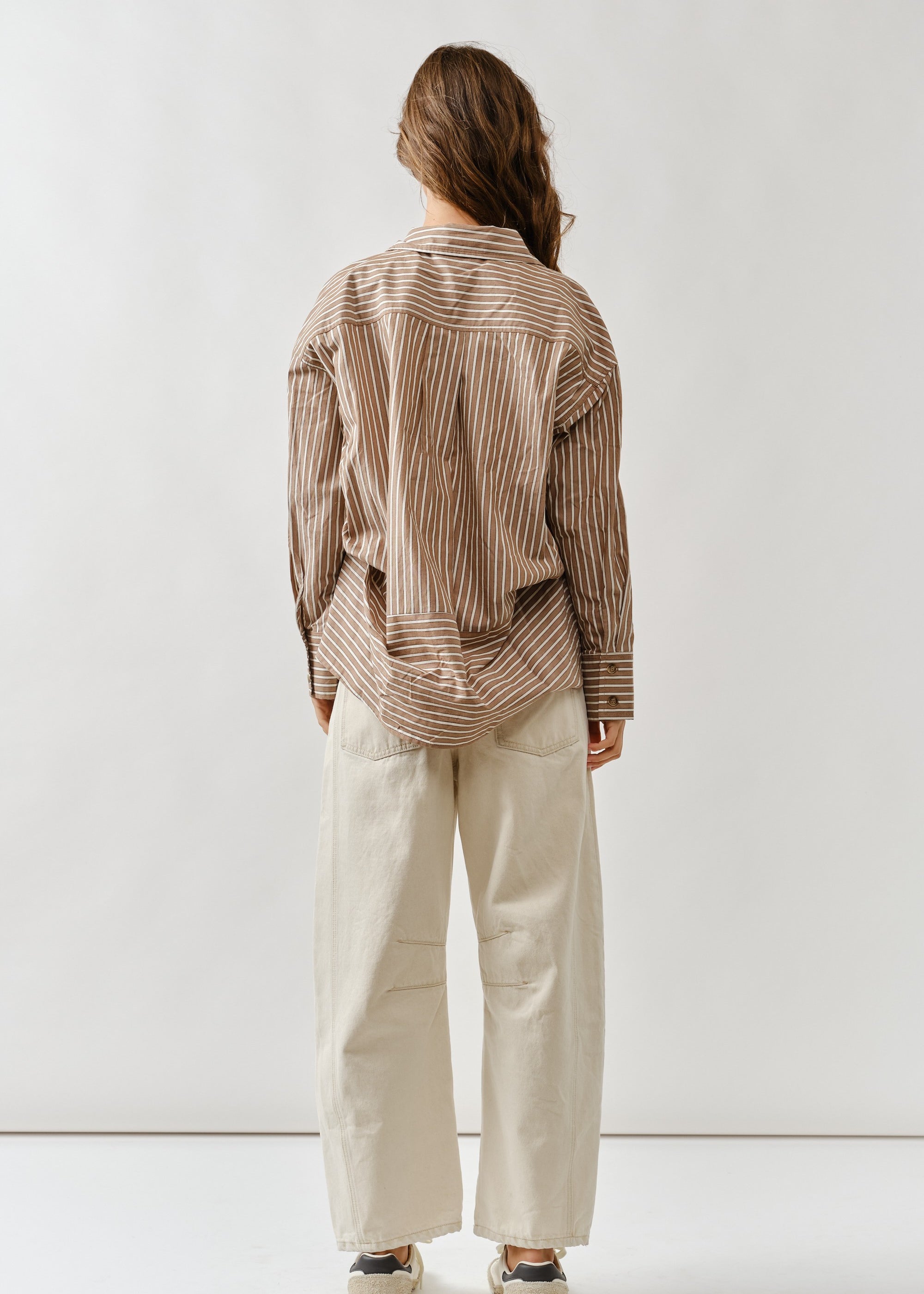 Side view highlighting the curved barrel-leg silhouette in beige