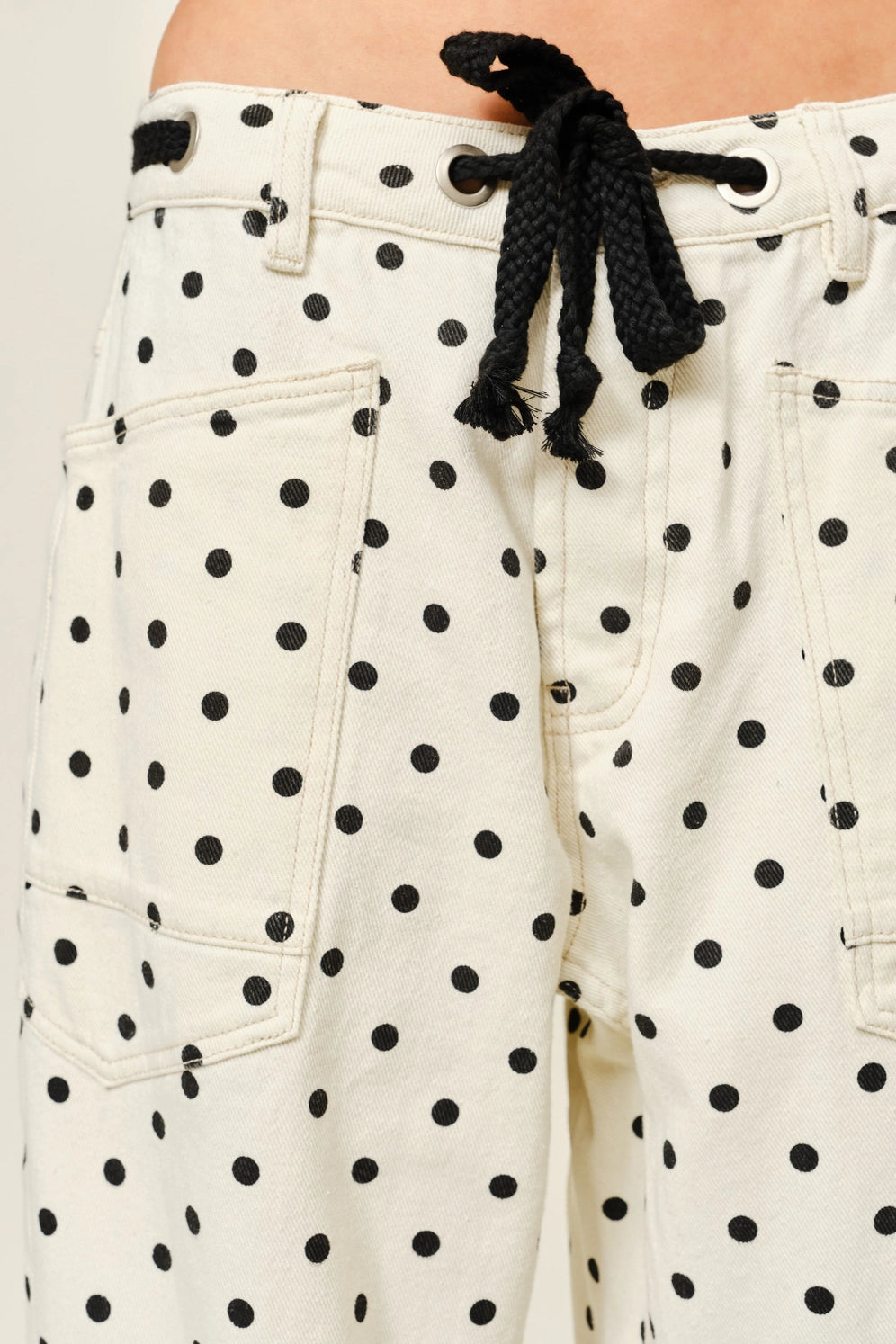 Close-up of Moxie Barrel Eyelet Jeans in polka dot cream showing eyelet waist and polka dot fabric
