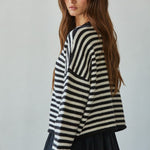 Side view of a black and white striped knit sweater showing the relaxed silhouette and long sleeves