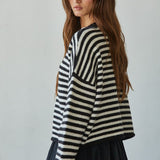 Side view of a black and white striped knit sweater showing the relaxed silhouette and long sleeves
