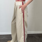 The Brooklin beige wide-leg pants with red side stripes, side view