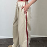 The Brooklin beige wide-leg pants with red side stripes, side view