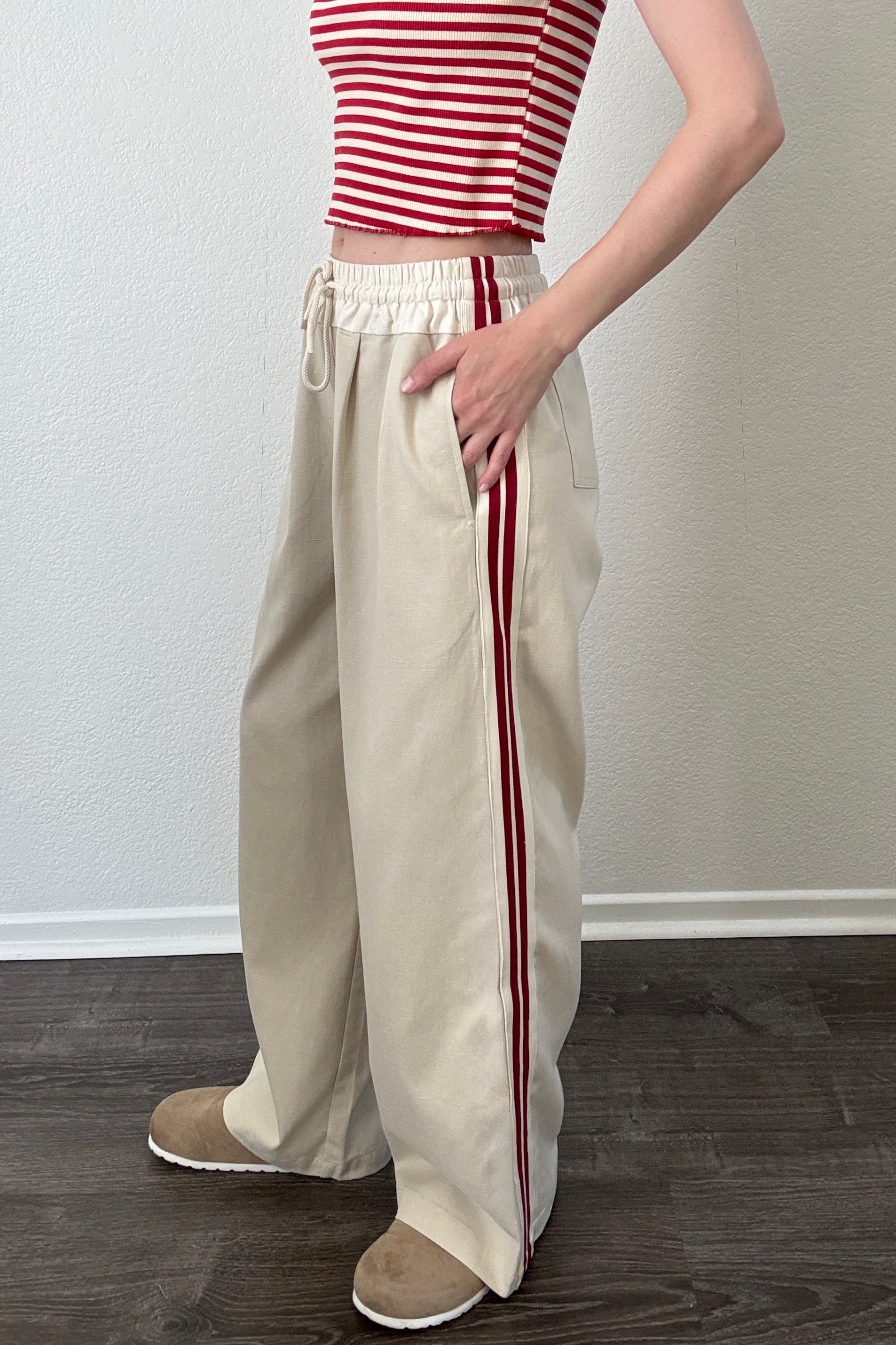 The Brooklin beige wide-leg pants with red side stripes, side view