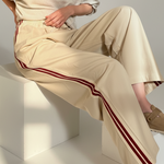 The Brooklin side-stripe pull-on wide-leg pants in beige styled in a seated outfit, featuring red side stripes and elastic tie waist