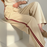The Brooklin side-stripe pull-on wide-leg pants in beige styled in a seated outfit, featuring red side stripes and elastic tie waist