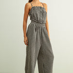 Woman wearing black and white gingham cotton jumpsuit with smocked top and relaxed barrel-leg silhouette