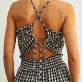 Open back detail of black and white gingham smocked jumpsuit with adjustable criss-cross straps