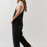 Side view of chill denim overall in black wash showing relaxed silhouette
