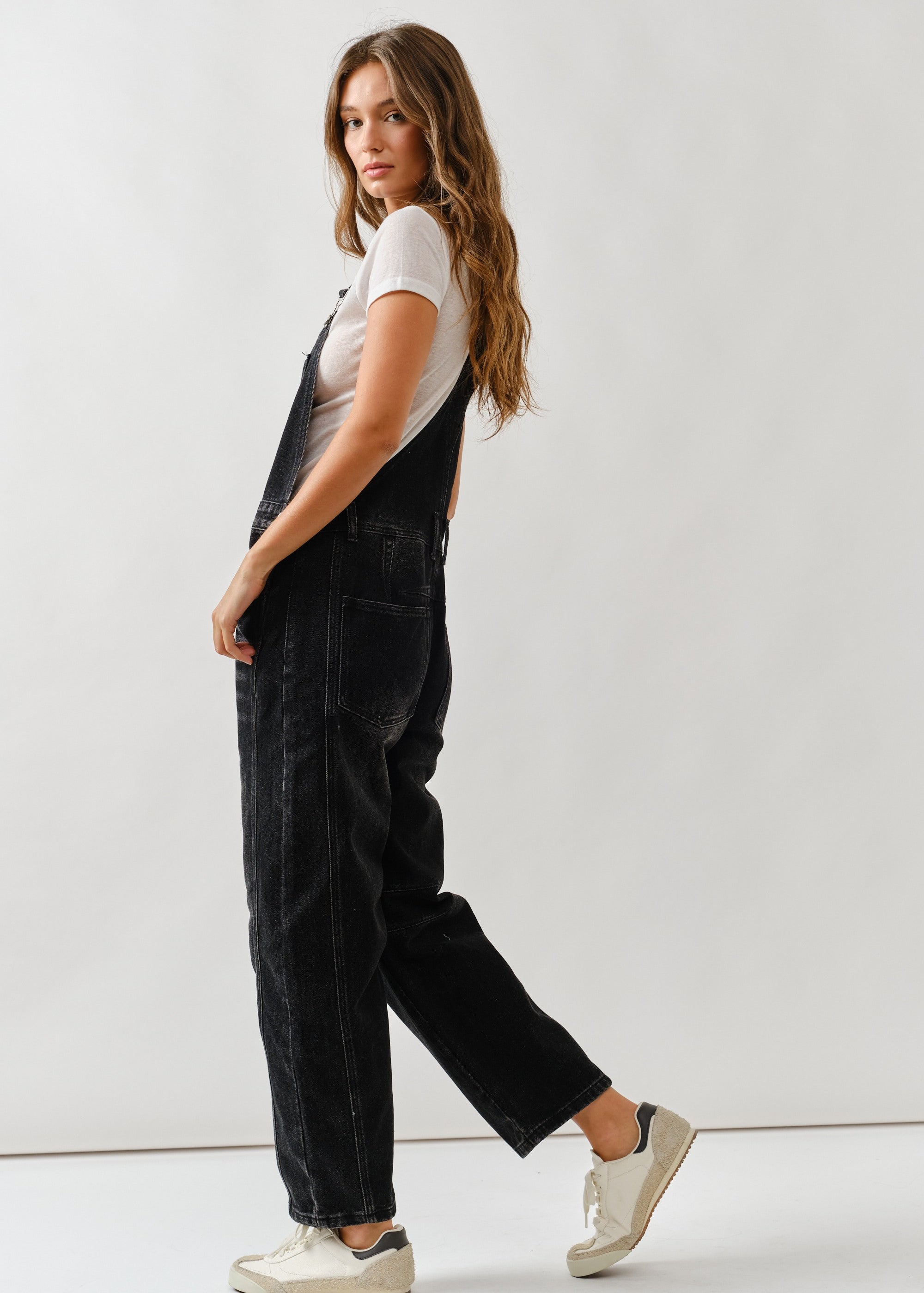 Side view of chill denim overall in black wash showing relaxed silhouette