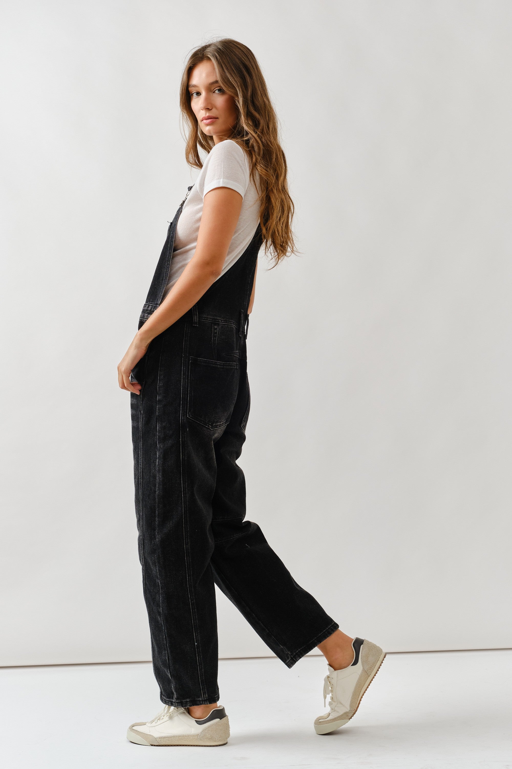 Side view of chill denim overall in black wash showing relaxed silhouette
