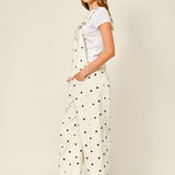 Side view of cream polka dot denim overalls with relaxed barrel legs