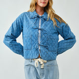 Woman wearing a blue quilted jacket and pants on a light gray background