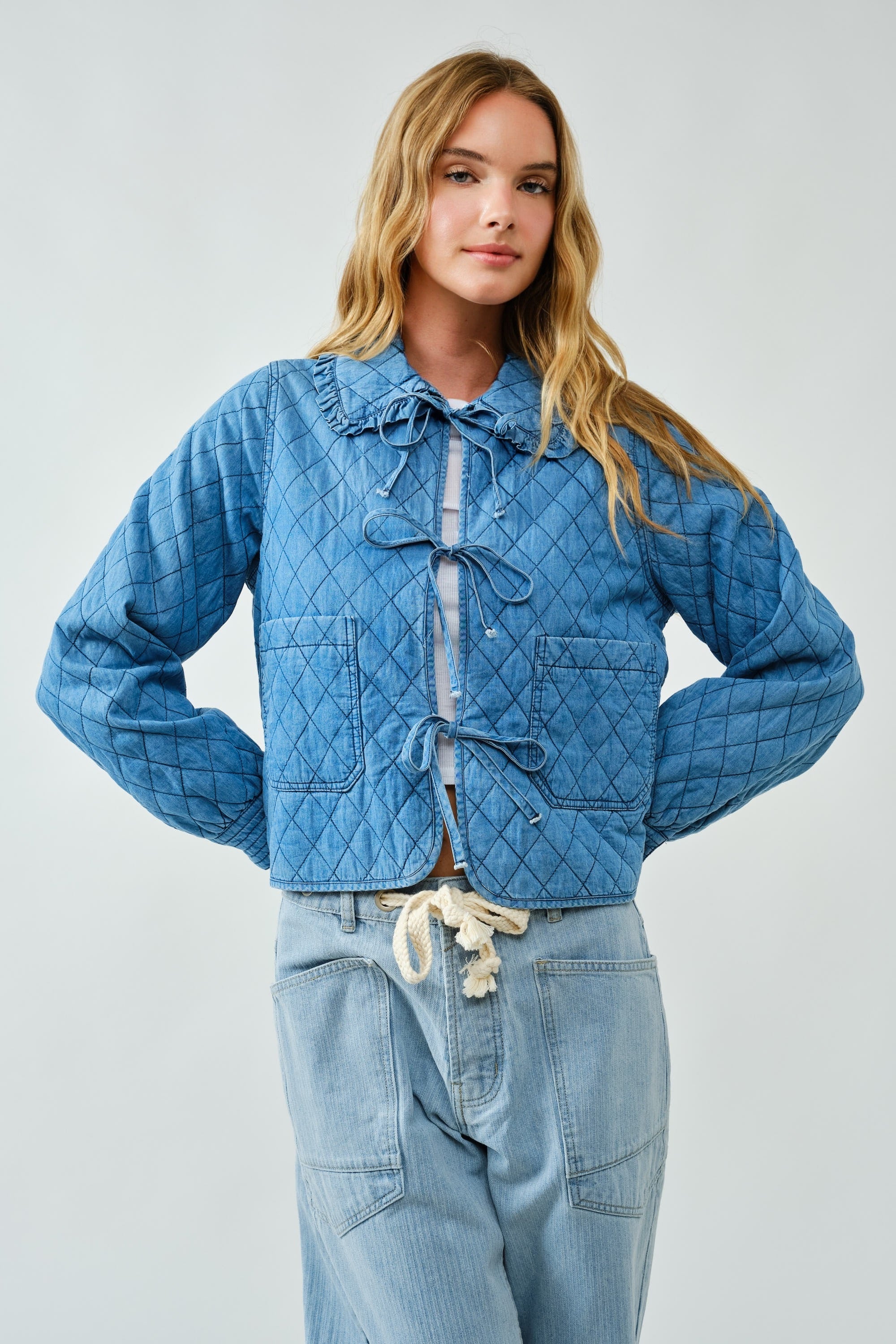 Woman wearing a blue quilted jacket and pants on a light gray background