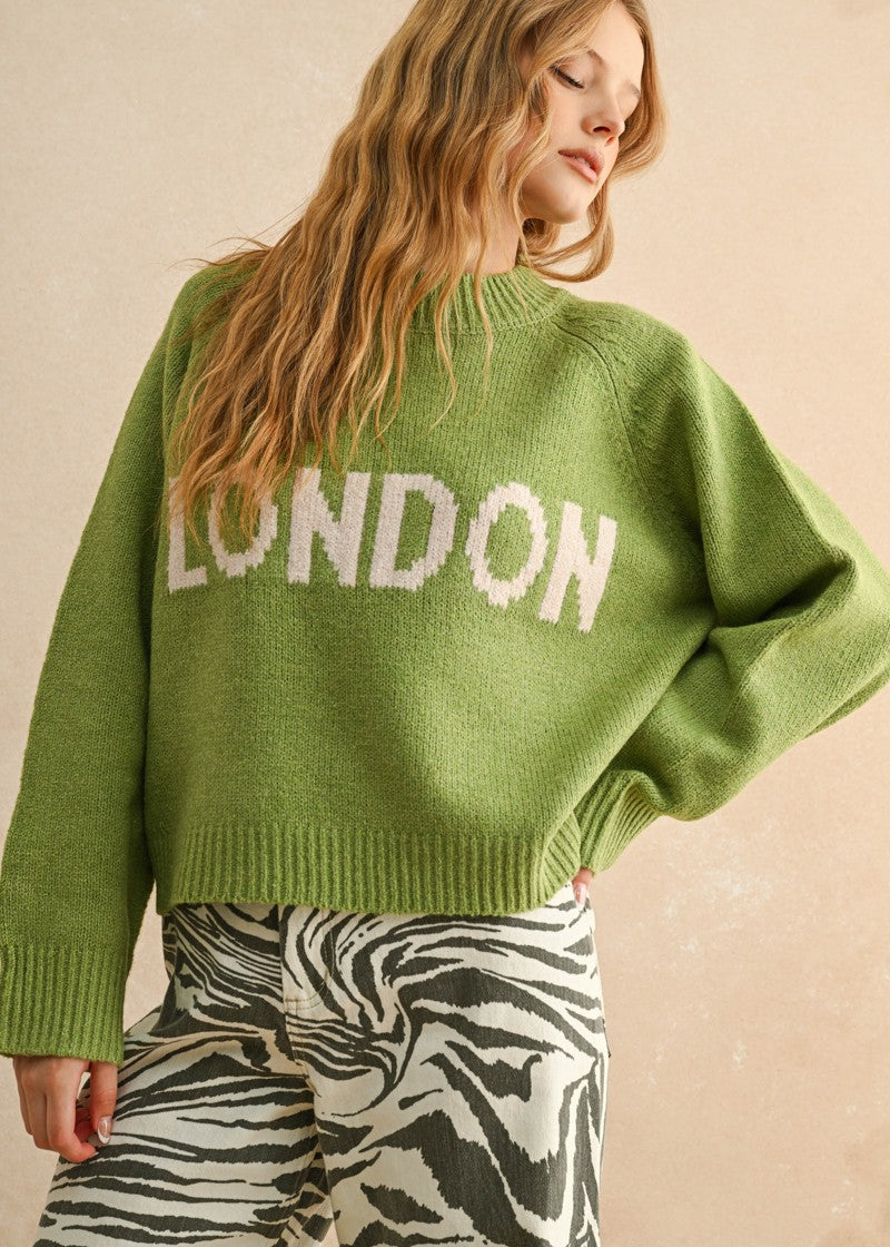Person wearing a green sweater with 'LONDON' text on a beige background
