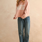 Full body view of city print casual sweater styled with jeans in Paris pink