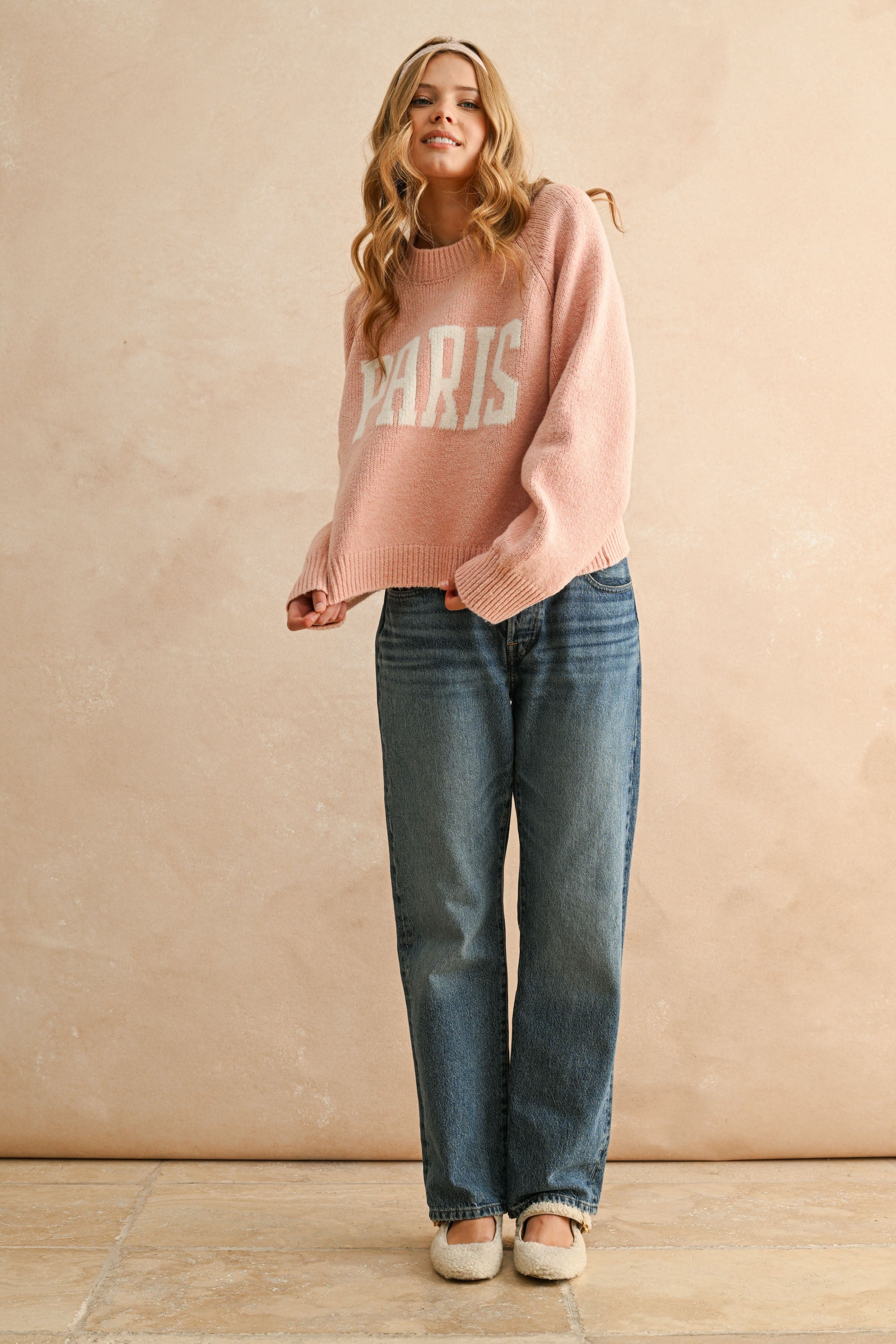 Full body view of city print casual sweater styled with jeans in Paris pink