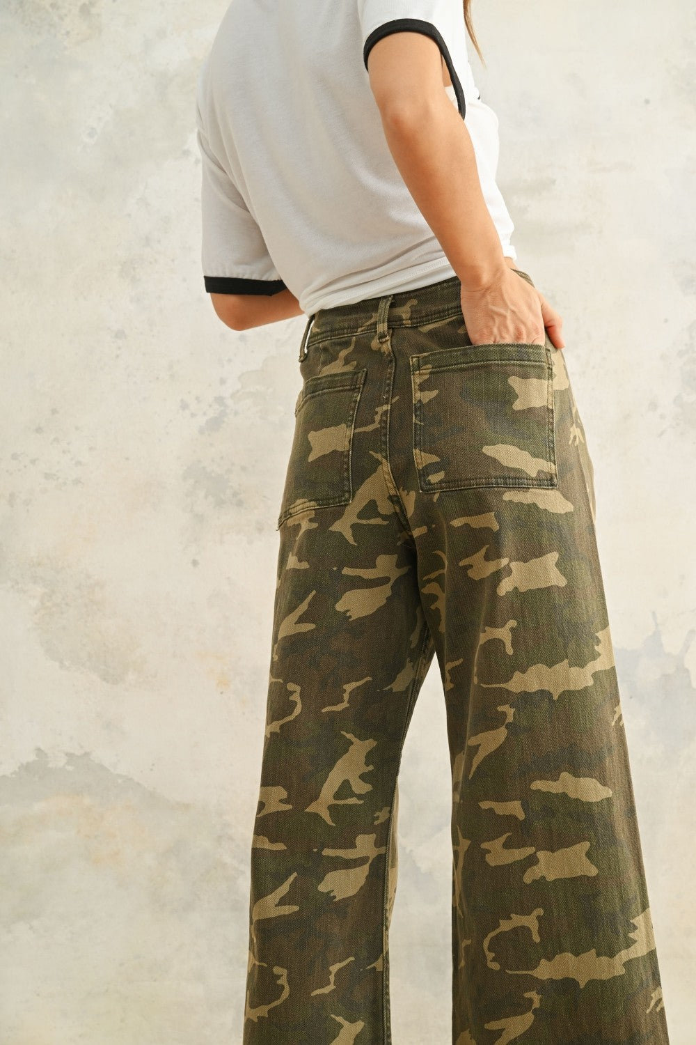 Close-up of Colette camouflage denim pants showing the stretch fabric, utility-inspired print, and raw hem detail.