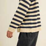 Person wearing a striped sweater with navy and beige colors on a plain background