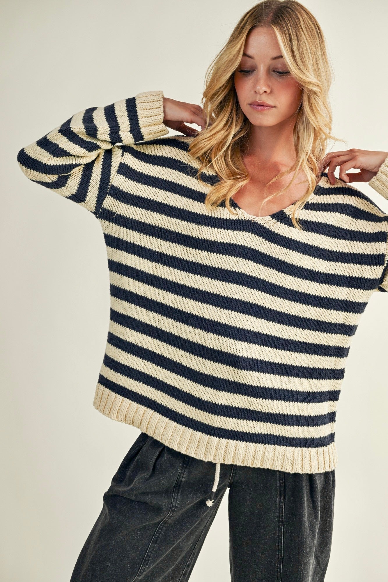 Woman wearing a striped sweater with a neutral background